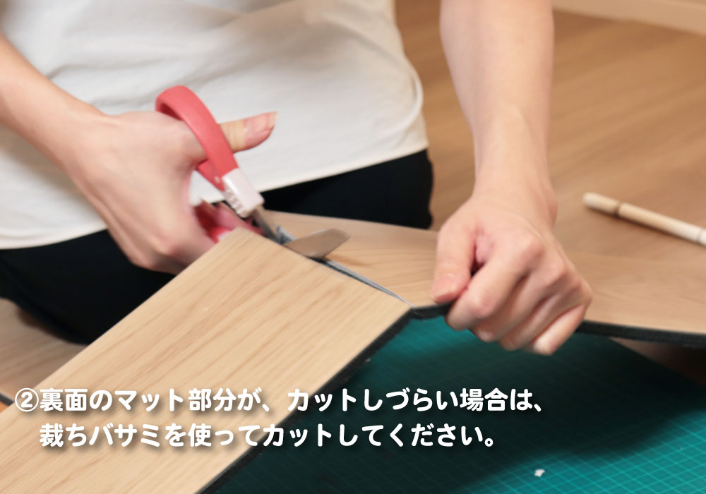 裏面のマット部分を裁ちバサミでカットしている足音マットWoodyの施工例。カッターで切りにくい場合もハサミで対応でき、賃貸住宅でも扱いやすい防音マットです。